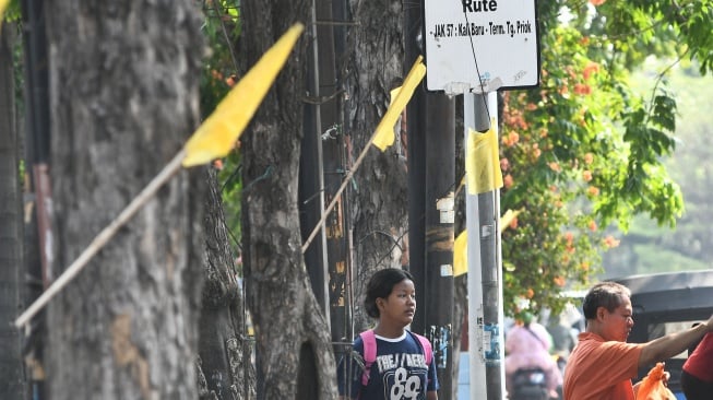 Sejumlah warga melintas disamping bendera kuning yang dipasang di Jalan Raya Plumpang Semper, Rawabadak, Jakarta Utara, Jumat (13/9/2024). [ANTARA FOTO/ Fakhri Hermansyah/Y]