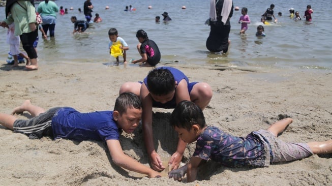 Pengunjung bermain air di Pantai Lagoon, Ancol Taman Impian, Jakarta, Senin (16/9/2024). [Suara.com/Alfian Winanto]