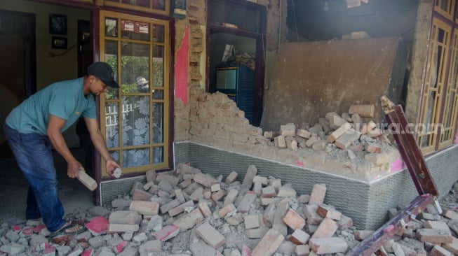 Warga membersihkan puing rumah yang runtuh pasca gempa bumi di Desa Cibeureum, Kertasari, Kabupaten Bandung, Jawa Barat, Rabu (18/9/2024). [ANTARA FOTO/Novrian Arbi/Spt]