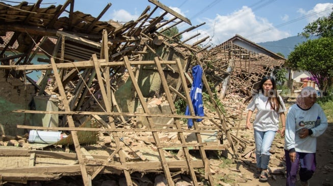 Warga melintas di dekat rumah yang rusak pasca gempa bumi di Desa Cibeureum, Kertasari, Kabupaten Bandung, Jawa Barat, Rabu (18/9/2024). [ANTARA FOTO/Novrian Arbi/Spt]
