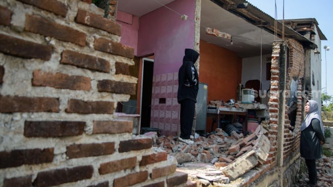 Warga memeriksa rumahnya yang rusak pasca gempa bumi di Desa Cibeureum, Kertasari, Kabupaten Bandung, Jawa Barat, Rabu (18/9/2024). [ANTARA FOTO/Novrian Arbi/Spt]
