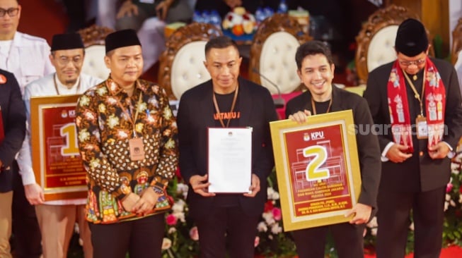 Pasangan Calon Gubernur dan Calon Wakil Gubernur Jakarta, Dharma Pongrekun - Kun Wardana menunjukan nomor saat mengikuti rapat pleno terbuka pengundian nomor urut peserta calon pemilihan kepala daerah di KPUD Jakarta, Senin (23/9/2024). [Suara.com/Alfian Winanto]