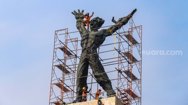 Petugas melakukan perawatan monumen Pembebasan Irian Barat di Lapangan Banteng, Jakarta Pusat, Kamis (26/9/2024). [Suara.com/Alfian Winanto]