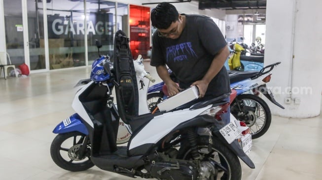 Teknisi mengonversi sepeda motor berbahan bakar minyak menjadi sepeda motor listrik di Bengkel Elders Garage, Jakarta, Jumat (4/10/2024). [Suara.com/Alfian Winanto]