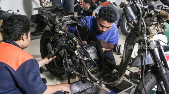 Teknisi mengonversi sepeda motor berbahan bakar minyak menjadi sepeda motor listrik di Bengkel Elders Garage, Jakarta, Jumat (4/10/2024). [Suara.com/Alfian Winanto]