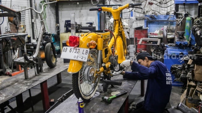 Teknisi mengonversi sepeda motor berbahan bakar minyak menjadi sepeda motor listrik di Bengkel Elders Garage, Jakarta, Jumat (4/10/2024). [Suara.com/Alfian Winanto]