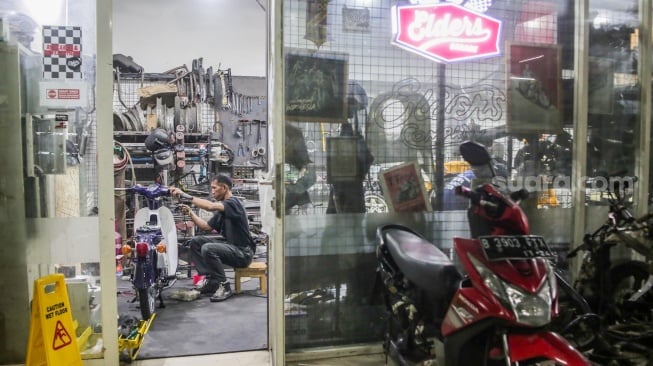 Teknisi mengonversi sepeda motor berbahan bakar minyak menjadi sepeda motor listrik di Bengkel Elders Garage, Jakarta, Jumat (4/10/2024). [Suara.com/Alfian Winanto]