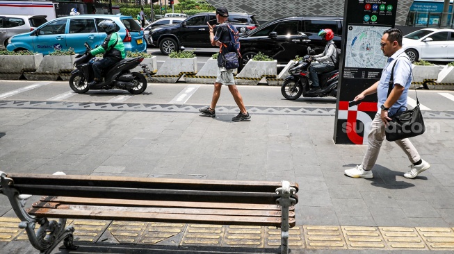 Warga beraktivitas saat fenomena hari tanpa bayangan di kawasan Bundaran Hotel Indonesia (HI), Jakarta, Selasa (8/10/2024). [Suara.com/Alfian Winanto]