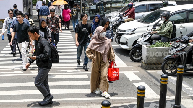 Warga beraktivitas saat fenomena hari tanpa bayangan di kawasan Bundaran Hotel Indonesia (HI), Jakarta, Selasa (8/10/2024). [Suara.com/Alfian Winanto]