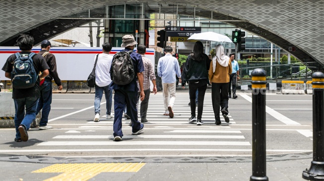 Warga beraktivitas saat fenomena hari tanpa bayangan di kawasan Bundaran Hotel Indonesia (HI), Jakarta, Selasa (8/10/2024). [Suara.com/Alfian Winanto]