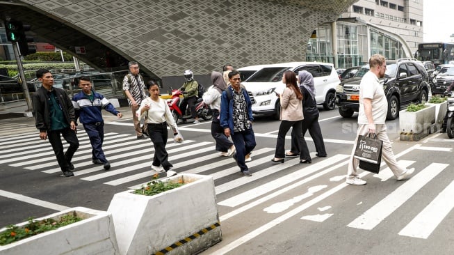 Warga beraktivitas saat fenomena hari tanpa bayangan di kawasan Bundaran Hotel Indonesia (HI), Jakarta, Selasa (8/10/2024). [Suara.com/Alfian Winanto]