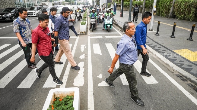 Warga beraktivitas saat fenomena hari tanpa bayangan di kawasan Bundaran Hotel Indonesia (HI), Jakarta, Selasa (8/10/2024). [Suara.com/Alfian Winanto]