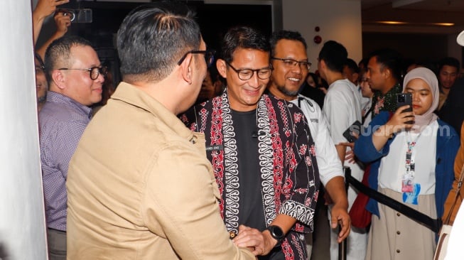 Menteri Parekraf Sandiaga Uno (kanan) dan Calon Gubernur Jakarta Ridwan Kamil (kiri) bersalaman saat bertemu di pameran Indonesian Contemporary Art and Design ke-14: Unexpected di Hotel Grandkemang, Jakarta, Rabu (9/10/2024). [Suara.com/Alfian Winanto]