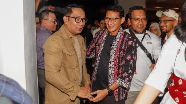 Menteri Parekraf Sandiaga Uno (kanan) dan Calon Gubernur Jakarta Ridwan Kamil (kiri) bersalaman saat bertemu di pameran Indonesian Contemporary Art and Design ke-14: Unexpected di Hotel Grandkemang, Jakarta, Rabu (9/10/2024). [Suara.com/Alfian Winanto]