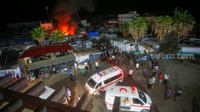 Api dan asap mengepul dari lokasi serangan udara Israel di sekitar tenda-tenda pengungsi di dalam tembok Rumah Sakit Martir Al-Aqsa di Deir al-Balah, di Jalur Gaza, Palestina, Senin (14/10/2024). [United Nations Relief and Works Agency for Palestine Refugees (UNRWA) / AFP]