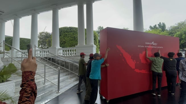 Sejumlah orang memindahkan backdrop foto yang sebelumnya digunakan untuk tempat berfoto tamu yang datang ke Kompleks Istana Kepresidenan, Jakarta. [Suara.com/Novian]