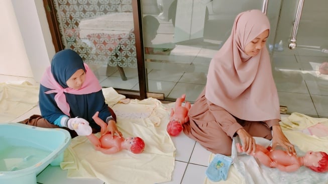 Peserta Sekolah Calon Ibu (SCI) melakukan praktik memandikan bayi dalam materi yang disiapkan. (dok.Istimewa)