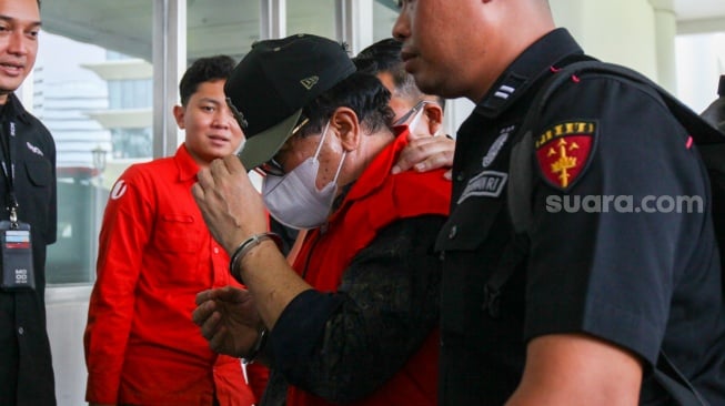 Petugas menggiring Hakim Pengadilan Negeri (PN) Surabaya Erintuah Damanik (tengah) saat akan menjalani pemeriksaan sebagai tersangka kasus dugaan tindak pidana korupsi di Jakarta, Selasa (5/11/2024). [Suara.com/Alfian Winanto]