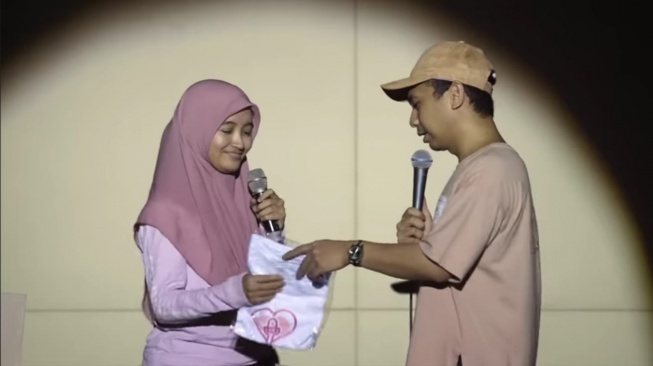Raditya Dika berikan kaos untuk Arafah Rianti dalam show standup Cerita Cintaku (YouTube/Raditya Dika)