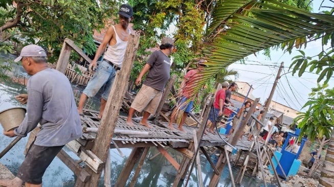 Warga saat gotong royong bangun jembatan di kawasan Batu Tumbuh, Jakarta Utara. Kini jembatan tersebut sudah direnovasi warga menggunakan besi agar lebih aman dan tahan lama. (Foto dok. warga)