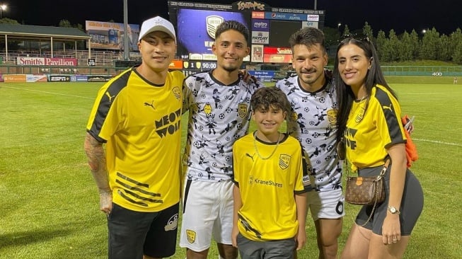 Mantan pemain Timnas Indonesia, Dipo Alam, dengan baju kuning (paling kiri) bersama istri (paling kanan) dan anaknya (tengah). (Instagram/@dipoalam_)