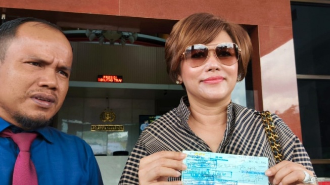 Irma Suryani bersama kuasa hukumnya Jumintar Napitupulu saat menunjukkan barang bukti cek kosong. [Presisi.co]