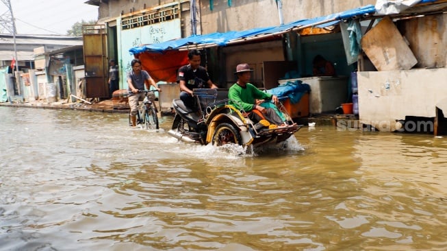 Warga beraktivitas di tengah banjir rob yang menggenangi wilayah Muara Angke, Jakarta Utara, Selasa (19/11/2024). [Suara.com/Alfian Winanto]