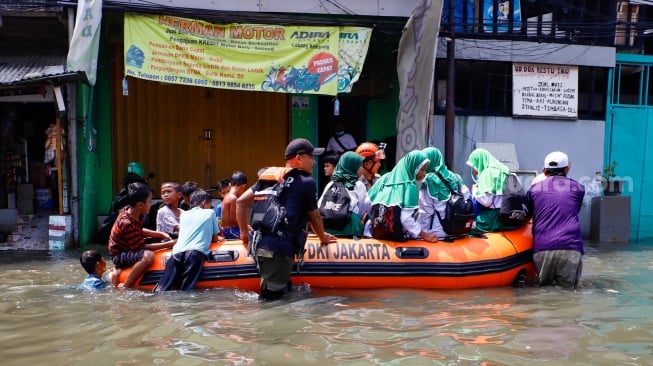 Warga beraktivitas di tengah banjir rob yang menggenangi wilayah Muara Angke, Jakarta Utara, Selasa (19/11/2024). [Suara.com/Alfian Winanto]