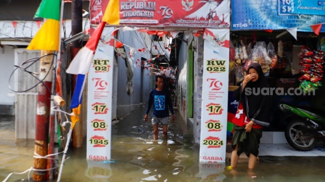 Warga beraktivitas di tengah banjir rob yang menggenangi wilayah Muara Angke, Jakarta Utara, Selasa (19/11/2024). [Suara.com/Alfian Winanto]