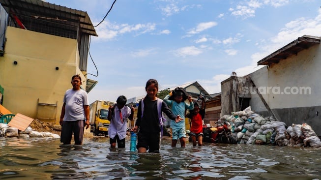 Warga beraktivitas di tengah banjir rob yang menggenangi wilayah Muara Angke, Jakarta Utara, Selasa (19/11/2024). [Suara.com/Alfian Winanto]