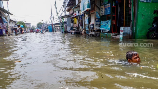 Warga beraktivitas di tengah banjir rob yang menggenangi wilayah Muara Angke, Jakarta Utara, Selasa (19/11/2024). [Suara.com/Alfian Winanto]