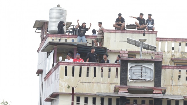 Potret suporter Malut United menyaksikan laga dari bangunan belakang Stadion Kie Raha, Ternate  saat melawan Persis Solo dalam lanjutan BRI Liga 1 2024/2025, Kamis (21/11/2024). [Persis Solo/ M Maftuh Mafazi]