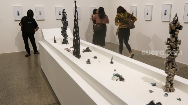 Pengunjung melihat pameran instlalasi seni 'Kawah Ojol' di Galeri ROH, Jakarta, Jumat (22/11/2024). [Suara.com/Alfian Winanto]