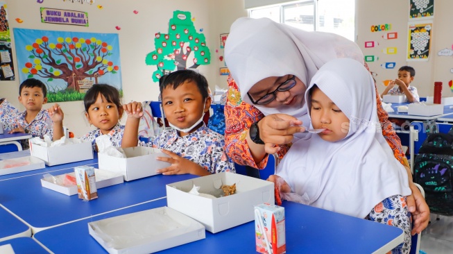 Para siswa menyantap makanan saat mengikuti uji coba Program Makan Bergizi gratis di SD Angkasa 5 Halim Perdana Kusuma, Jakarta, Selasa (26/11/2024). [Suara.com/Alfian Winanto]