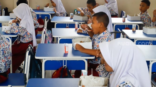 Para siswa menyantap makanan saat mengikuti uji coba Program Makan Bergizi gratis di SD Angkasa 5 Halim Perdana Kusuma, Jakarta, Selasa (26/11/2024). [Suara.com/Alfian Winanto]