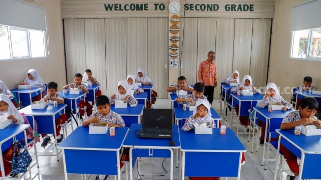 Para siswa menyantap makanan saat mengikuti uji coba Program Makan Bergizi gratis di SD Angkasa 5 Halim Perdana Kusuma, Jakarta, Selasa (26/11/2024). [Suara.com/Alfian Winanto]