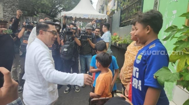 Cagub Jakarta Ridwan Kamil kaget bertemu bocah berjersey Jakmania-Viking di dekat TPS, Ciumbuleuit, Cidadap, Jawa Barat. (Suara.com/Fakhri)