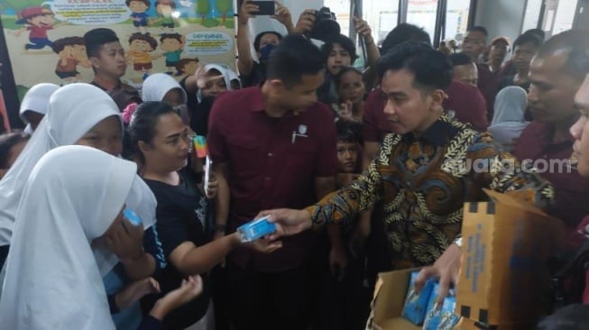 Wapres Gibran Rakabuming Raka saat bagi-bagi susu kepada warga korban banjir di Kebon Pala, Jakarta Timur. (Suara.com/Moh Reynaldi Risahondua). 