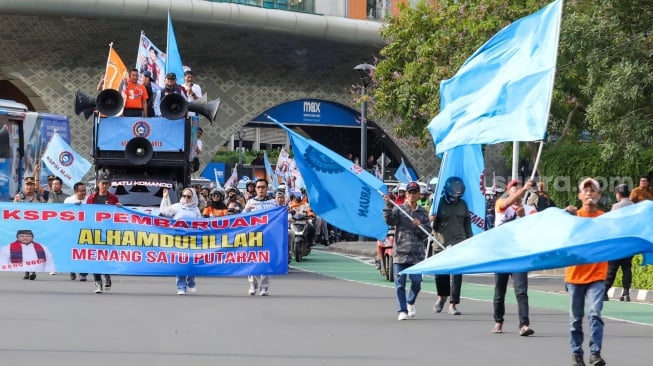 Massa dari Konfederasi Serikat Pekerja Indonesia (KSPI) melakukan pawai kemenangan satu putaran untuk paslon gubernur-wakil gubernur nomor urut 3 Pramono Anung-Rano Karno di Bundaran HI, Jakarta, Jumat (29/11/2024). [Suara.com/Alfian Winanto]