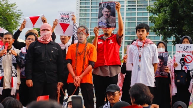 Massa membuat teaterika penangkapan Netanyahu saat aksi solidaritas untuk Palestina di depan Kedutaan Besar Amerika di Jakarta, Jumat (29/11/2024). [Suara.com/Alfian Winanto]