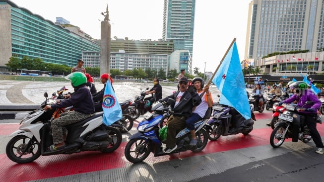 Massa dari Konfederasi Serikat Pekerja Indonesia (KSPI) melakukan pawai kemenangan satu putaran untuk paslon gubernur-wakil gubernur nomor urut 3 Pramono Anung-Rano Karno di Bundaran HI, Jakarta, Jumat (29/11/2024). [Suara.com/Alfian Winanto]