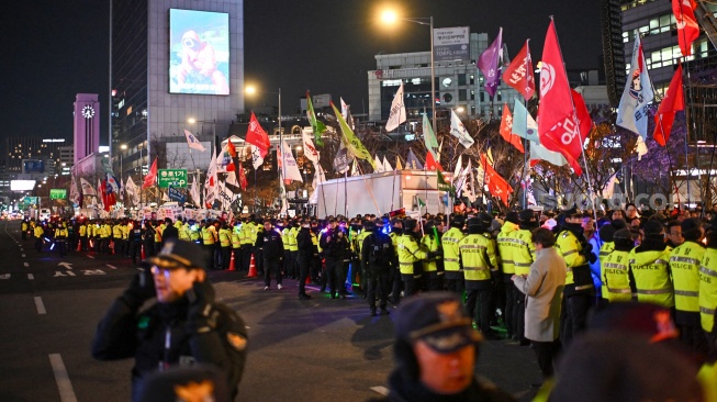 Orang-orang menyerukan pengunduran diri Presiden Korea Selatan Yoon Suk Yeol saat mereka mengambil bagian dalam protes di tangga menuju Majelis Nasional di Seoul, Korea Selatan, Rabu (4/12/2024). [Anthony WALLACE / AFP]