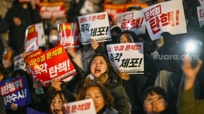 Orang-orang ambil bagian dalam protes yang menyerukan pengunduran diri Presiden Korea Selatan Yoon Suk Yeol di Majelis Nasional di Seoul, Korea Selatan, Rabu (4/12/2024). [Anthony WALLACE / AFP]