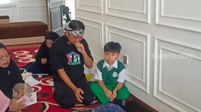 Tangis Ade Jigo di samping jenazah anaknya yang berusia 7 bulan, ditemui di rumah duka kawasan Ciputat, Tangerang Selatan pada Rabu (4/12/2024). [Suara.com/Rena Pangesti]