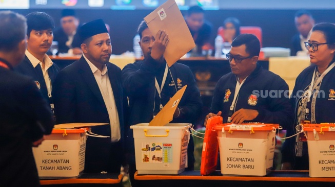 Petugas PPK Kecamatan Kemayoran membuka kotak berisi amplop form C hasil perhitungan suara disaksikan anggota KPU Kota Jakarta Pusat dan Bawaslu Kota Jakarta Pusat saat rapat pleno terbuka rekapitulasi hasil penghitungan perolehan suara dalam Pilkada serentak tahun 2024 di KotaJakarta Pusat, Rabu (4/12/2024). [Suara.com/Alfian Winanto]