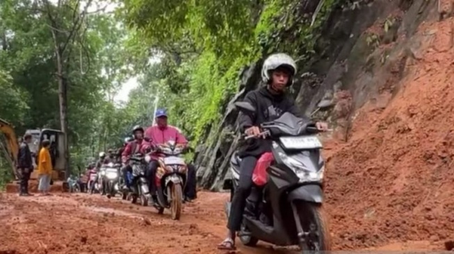 Sepeda motor sudah dapat melintas di Jalan Raya Pagelaran-Tanggeung, Cianjur, Jawa Barat, setelah petugas dari dinas terkait melakukan sodetan di tebing untuk membuat akses jalan baru, Kamis (5/12/2024).(ANTARA/Ahmad Fikri)