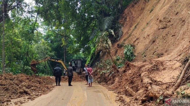 Petugas Dinas Binamarga Propinsi Jawa Barat, membersihjkan material longsor yang menutup jalur utama Cianjur selatan di Kecamatan Pagelaran sehingga dapat dilalui kendaran secara bergantian, Jumat (6/12/2024).(ANTARA/Ahmad Fikri).