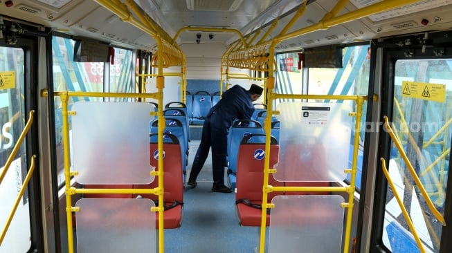 Petugas melihat kondisi di dalam bus listrik Transjakarta berjejer di Lapangan Silang Monas, Jakarta, Selasa (10/12/2024). [Suara.com/Alfian Winanto]