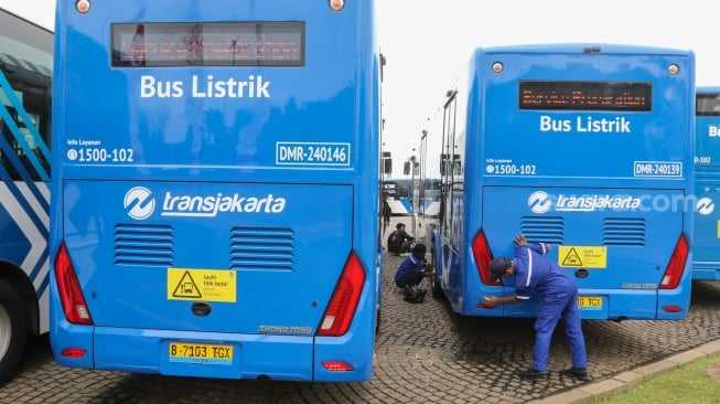 Petugas melihat kondisi bus listrik Transjakarta di Lapangan Silang Monas, Jakarta, Selasa (10/12/2024). [Suara.com/Alfian Winanto]