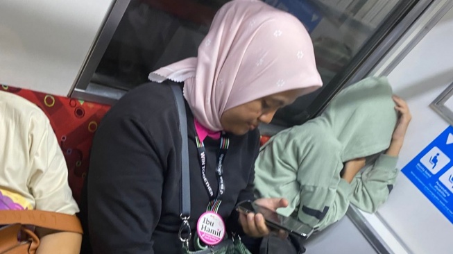 Ibu hamil menggunakan pin di bangku prioritas KRL. [Suara.com/Lilis Varwati]